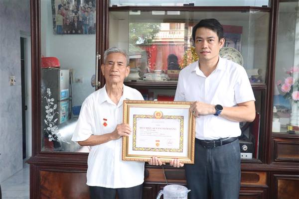 Đồng chí Phó Bí thư Thường trực Đảng uỷ xã trao Huy hiệu 60 năm tuổi Đảng tại gia đình cho 2 đảng viên cao tuổi