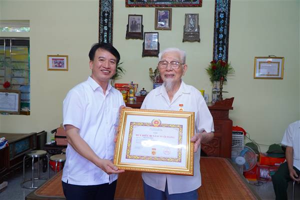 Đồng chí Nguyễn Đức Tuấn - Ủy viên Ban Thường vụ Thành ủy, Phó chủ tịch Thường trực UBMTTQ Việt Nam thành phố trao Huy hiệu 80 năm tuổi Đảng cho đảng viên Hà Văn Tiến