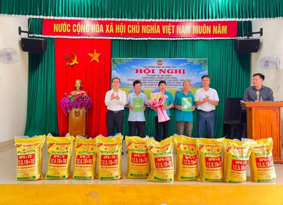 A group of people standing in front of a stage with bags of rice
Description automatically generated